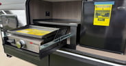 A propane flat-top griddle and mini fridge in the outside kitche