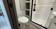 A cabinet door conceals some storage cubbies in the bathroom of