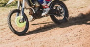 Motocross rider driving on dirt track leaving dust cloud