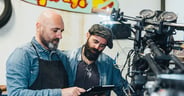 Two mature men, working in garage, using digital tablet